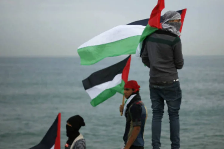 
	Manifestantes palestinos seguram bandeiras em Gaza: pelo menos, uma pessoa ficou ferida de forma leve nos ataques
 (Suhaib Salem/Reuters)