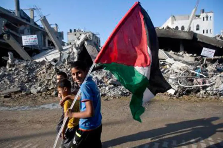 
	Crian&ccedil;as palestinas caminham diante de casas destru&iacute;das na Faixa de Gaza ap&oacute;s ataque em agosto
 (Mahmud Hams/AFP)
