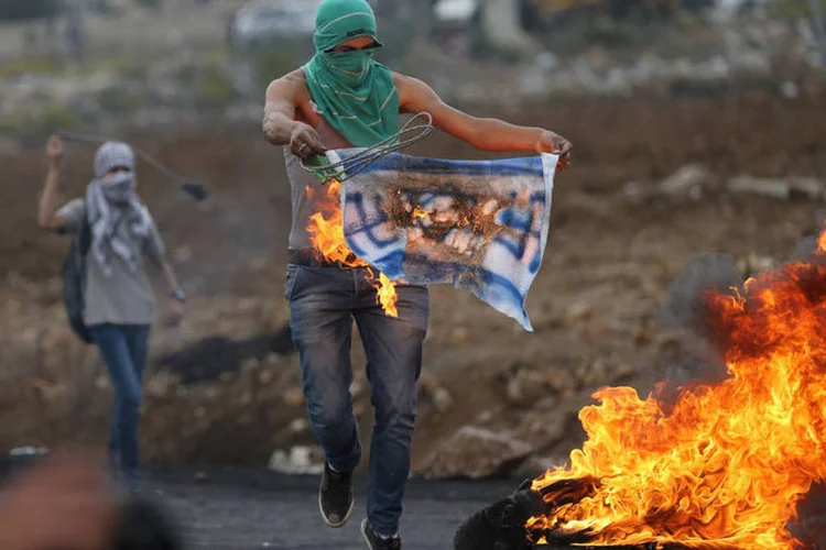 
	Palestino queima r&eacute;plica de bandeira de Israel em protesto: Nahson afirmou ainda que a Unesco juntou-se aos que querem por fogo nos lugares mais sens&iacute;veis da humanidade, referindo-se &agrave; Esplanada das Mesquitas
 (Reuters / Mohamad Torokman)
