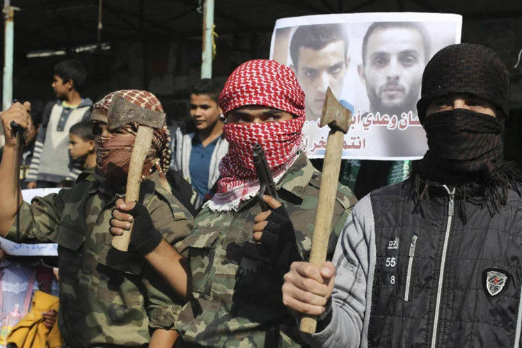 
	Palestinos mascarados seguram machados e arma para celebrar atentado contra sinagoga em Jerusal&eacute;m
 (Ibraheem Abu Mustafa/Reuters)