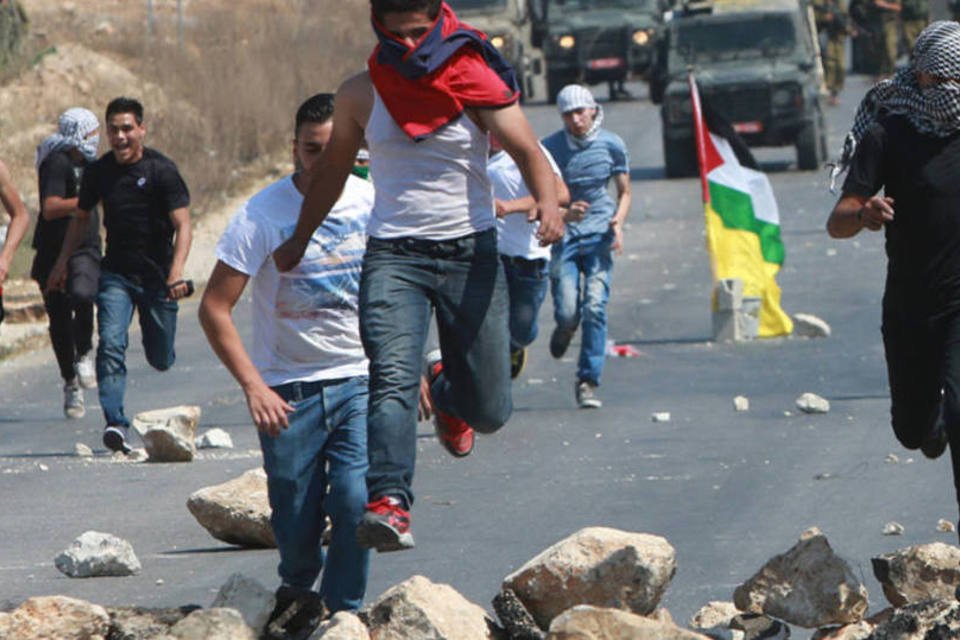 
	Palestinos fogem de israelenses: defensores do casal distribu&iacute;ram rosas e carregaram cartazes
 (Abed Omar Qusini/Reuters)