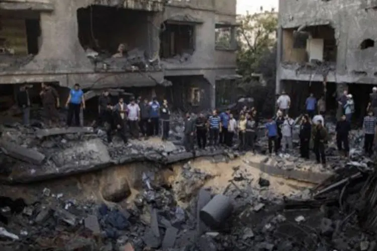 
	Palestinos ao redor de cratera causada por ataque israelense na Cidade de Gaza
 (Marco Longari/AFP)