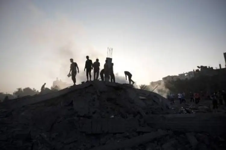 
	Palestinos em pr&eacute;dio destru&iacute;do em Gaza: doze palestinos j&aacute; morreram
 (Mahmud Hams/AFP)