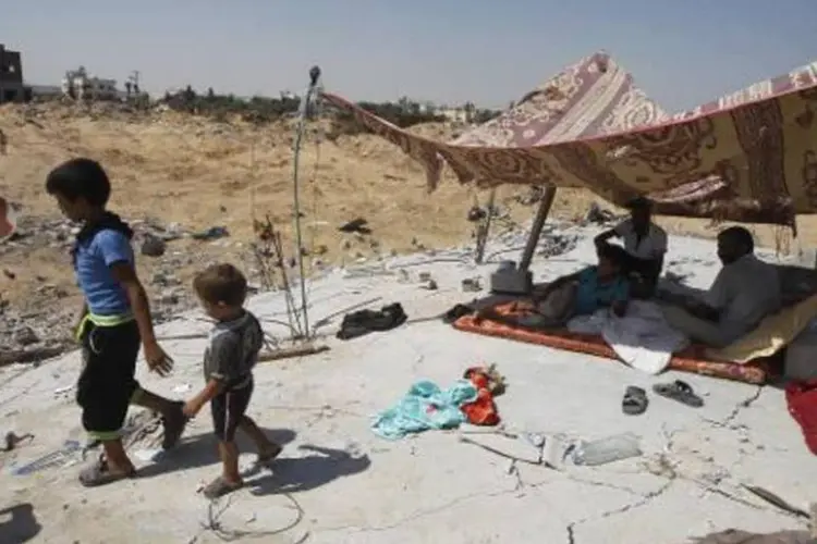 Palestinos em uma barraca sobre os escombros de uma casa que foi destruída por um ataque aéreo israelense em Abasan, perto da fronteira com Israel (Said Khatib/AFP)