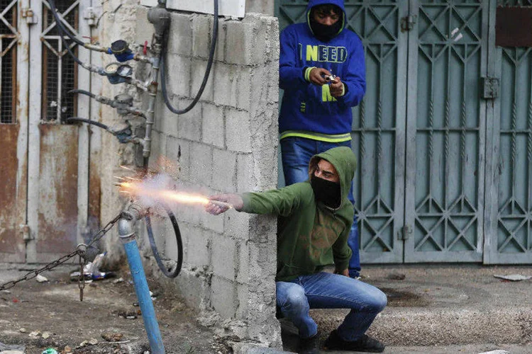 Palestinos usam fogos de artifício durante confrontos com forças de segurança israelenses, próximo a Jerusalém (Ammar Awad/Reuters)