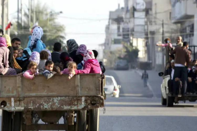 Palestinos deslocados, que fugiram de suas casas, pegam carona em um caminhão em direção a uma escola usada como base da Organização das Nações Unidas (ONU) em Gaza  (REUTERS / Majdi Fathi)