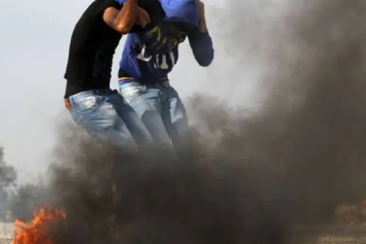 Universitários contrários à ação militar na Faixa de Gaza protegem a cabeça: dois palestinos foram "mortos por um novo disparo israelense a leste de al-Boureij" (©AFP / Abbas Momani)