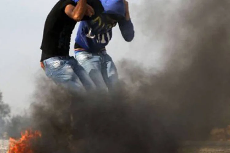Universitários contrários à ação militar na Faixa de Gaza protegem a cabeça: dois palestinos foram "mortos por um novo disparo israelense a leste de al-Boureij" (©AFP / Abbas Momani)