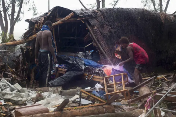 Família observa os escombros de sua casa destruída: O ciclone Pam teve seu pico de intensidade ontem (13) à noite, com ventos que atingiram, em média, 250 a 270 quilômetros por hora  (Reuters)