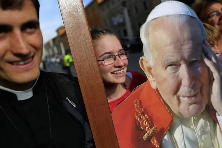 Fiéis tiram fotos com a imagem do papa João Paulo II em frente a praça de São Pedro, em Roma (Tony Gentile/Reuters)