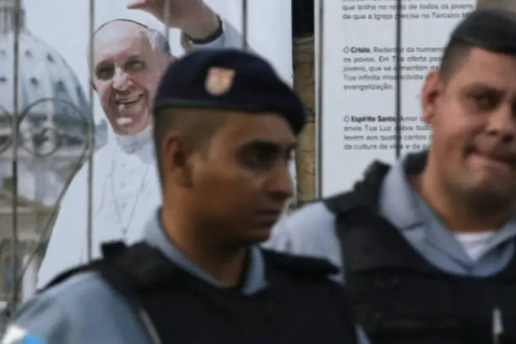 Policiais de UPP em frente a cartaz com a imagem do Papa Francisco em favela do Rio de Janeiro (REUTERS/Ricardo Moraes)