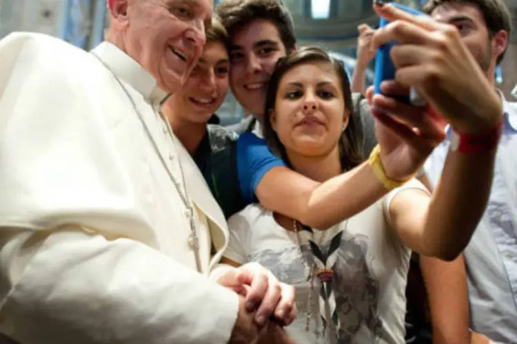 Na Basílica de São Pedro, no Vaticano, o Papa Francisco tira uma "selfie" no celular com jovens católicos. (28/8/2013) (Osservatore Romano/EPA)