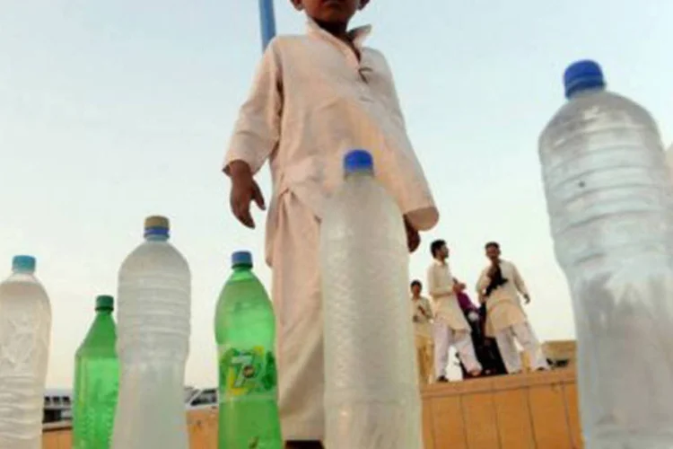 Criança paquistanesa vende garrafas de água em uma praia de Karachi: a ameba Naegleria fowleri vive em águas estagnadas e na terra úmida (©AFP / Rizwan Tabassum)