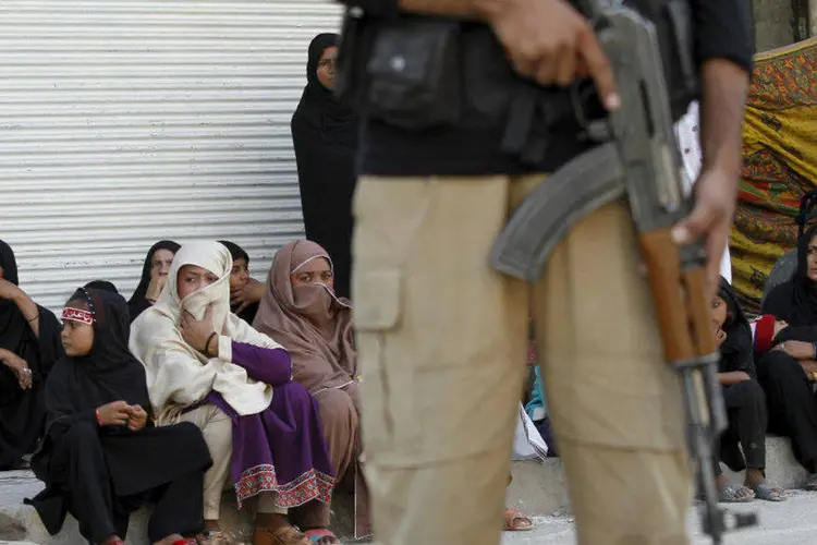 
	Policial e mulheres na prociss&atilde;o de Muharram, quando os xiitas realizam a festa da &quot;ashura&quot;, no Paquist&atilde;o
 (REUTERS/Fayaz Aziz)