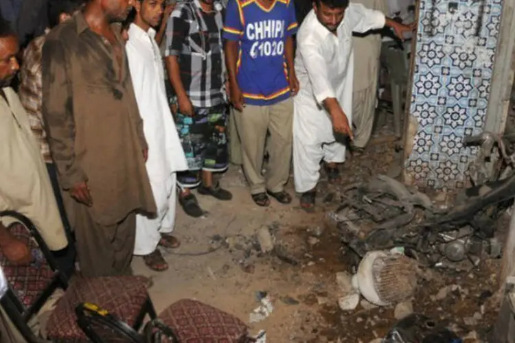 Simpatizantes do Partido do Povo Paquistanês observam destroços após atentado em Karachi (AFP / Asif Hassan)