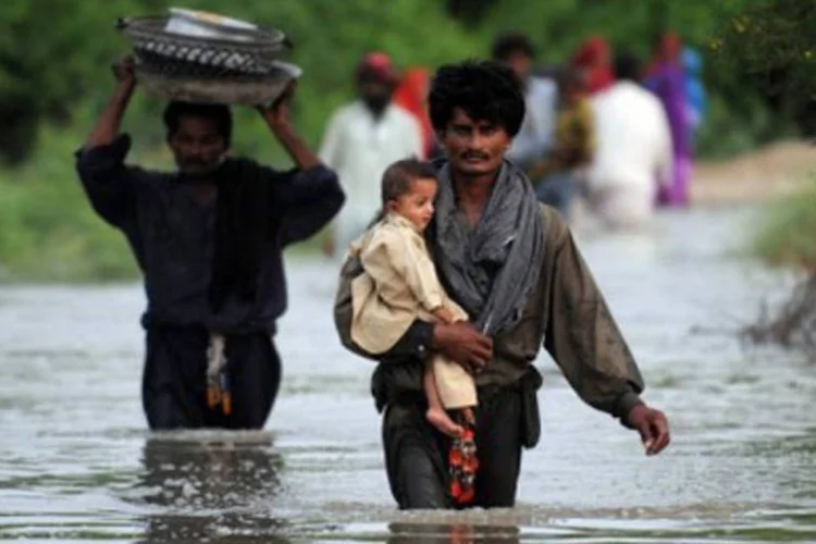Paquistaneses caminham em região alagada em Tando Hafiz Shah, a cerca de 60 km de Tatta, no Paquistão (Rizwan Tabassum/AFP)