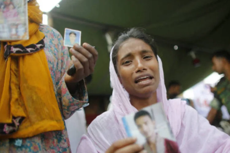 Mulheres seguram fotos de familiares que continuam desaparecidos após o desabamento de prédio em Bangladesh que deixou pelo menos 292 mortos (REUTERS/Andrew Biraj)