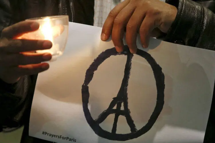 Um homem segura desenho de paz com a Torre Eiffel, durante vigília em Londres: símbolo se espalhou pelo mundo (REUTERS/Peter Nicholls)