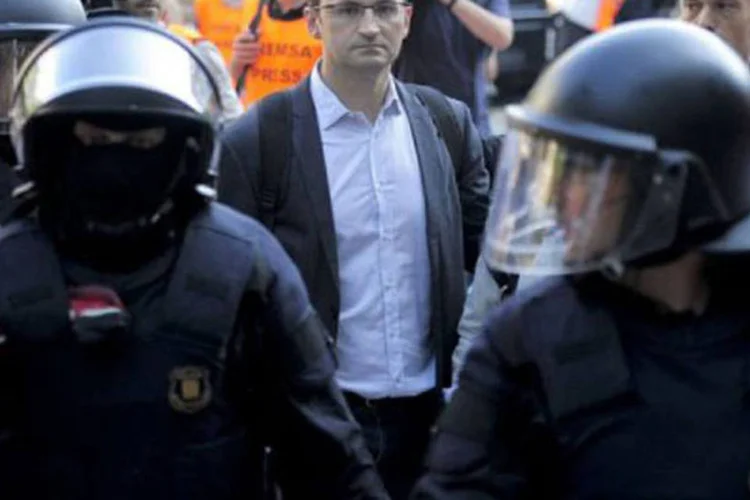 Polícia escolta o deputado catalão Joan Herrera:  agentes tiveram de formar um corredor humano para permitir a entrada dos parlamentares (Josep Lago/AFP)