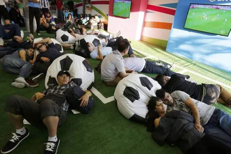 Passageiros relaxam enquanto veem um jogo da Copa do Mundo no Aeroporto de Guarulhos (Murad Sezer/Reuters)