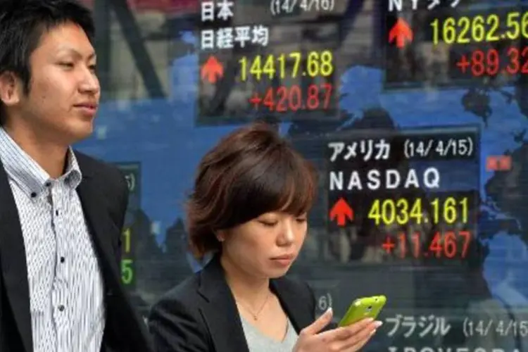 Pedestres passam em frente a painel de ações em Tóquio: banqueiro convenceu clientes a deixarem suas economias com ele para que fizesse investimentos (Yoshikazu Tsuno/AFP)