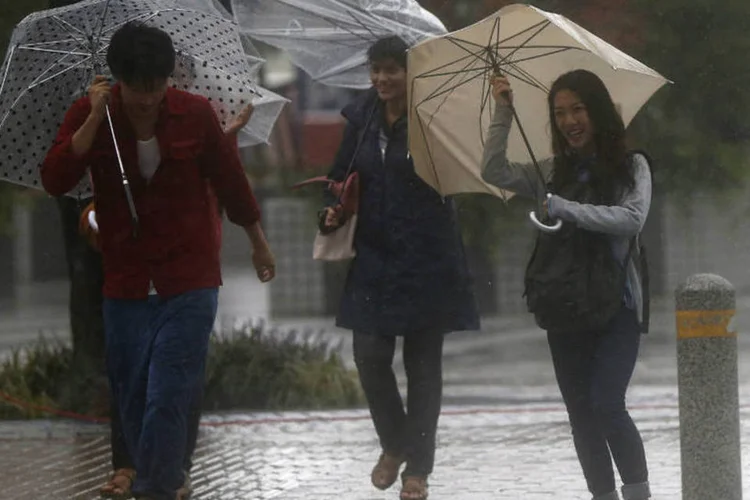 Pedestres com guarda-chuvas durante chuvas causadas pelo tufão Phanfone (Issei Kato/Reuters)