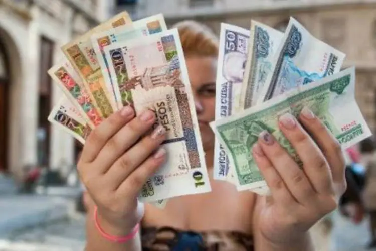 Cubana segura notas de pesos cubanos e pesos conversíveis em Havana (Yamil Lage/AFP)