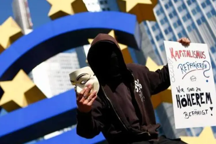 Pessoa protesta diante da escultura do euro na frente do BCE, em Frankfurt (Kai Pfaffenbach/Reuters)