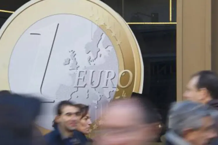
	Pessoas passam em frente a pr&eacute;dio com cartaz da moeda de euro: a queda afeta as quatro maiores economias da Eurozona, Alemanha, Fran&ccedil;a, It&aacute;lia e Espanha
 (AFP)