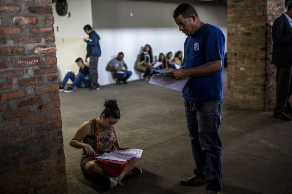 Pessoas preenchem formulários em feira de emprego no Rio de Janeiro (Dado Galdieri/Bloomberg)