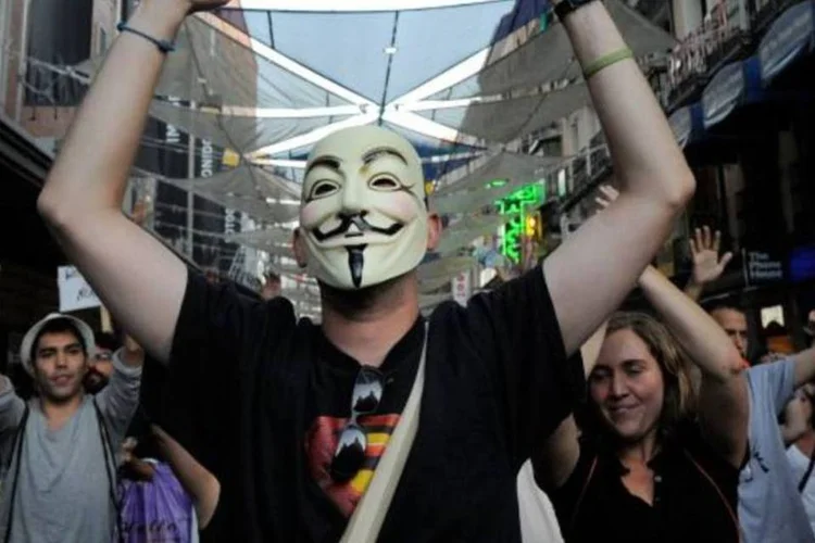 Pessoas protestam na praça Puerta del Sol, homem usa máscara similar aos dos hackers do grupo Anonymous (Denis Doyle/Getty Images)