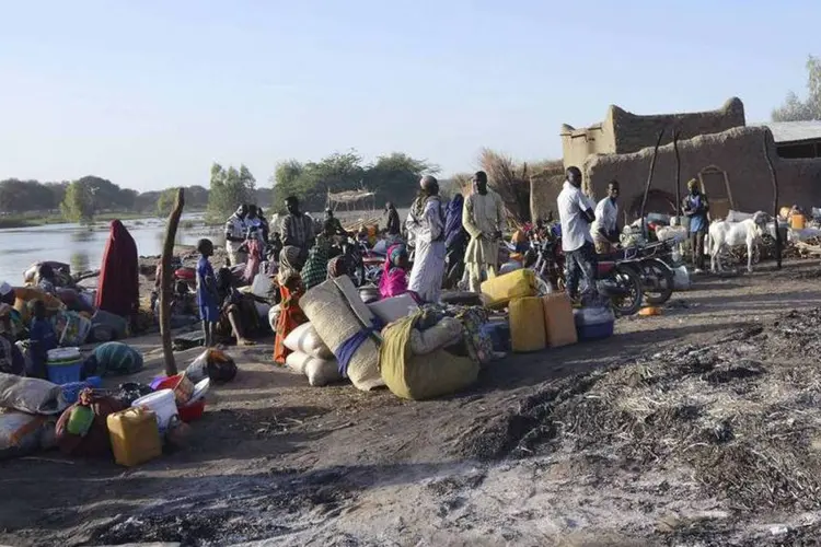 
	Pessoas se preparam para fugir de um vilarejo: sobreviventes do ataque situam o n&uacute;mero de mortos em mais cem, muitos dos corpos foram levados pela correnteza
 (Madjiasra Nako/Reuters)