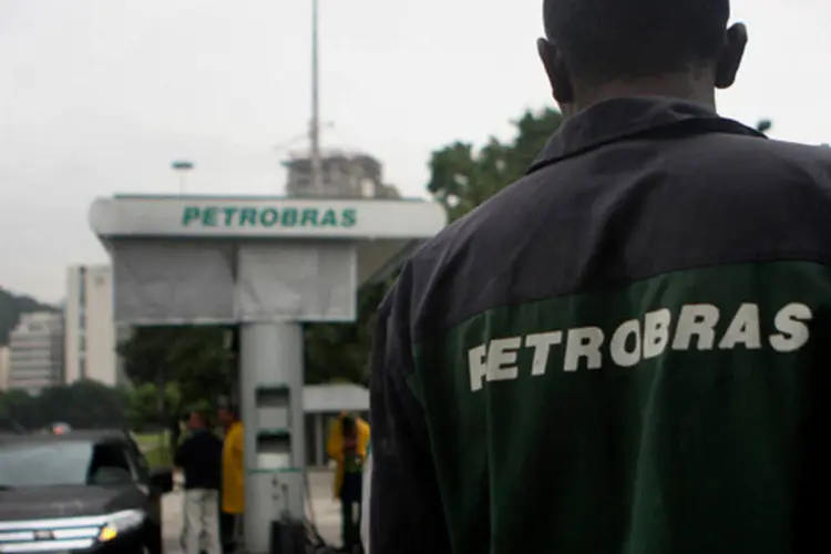 
	Frentista olha um carro sendo abastecido em um posto de gasolina da Petrobras no Rio de Janeiro
 (Dado Galdieri/Bloomberg)