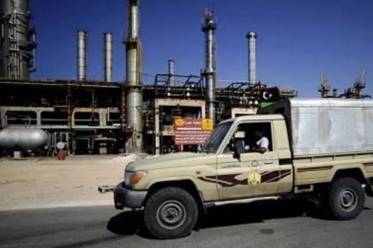 Rebeldes passam pela refinaria de petróleo na Líbia: não se sabe se entre as petrolíferas que podem ter as sanções cortadas está a principal companhia líbia do setor, a NOC
 (Filippo Monteforte/AFP)