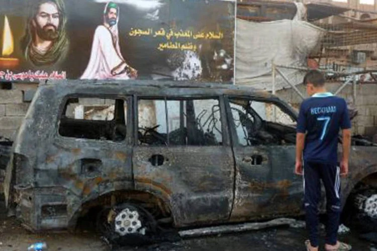 Garoto observa carro utilizado em ataque: suicida detonou explosivos dentro de uma tenda instalada para um funeral (Ali al-Saadi/AFP)