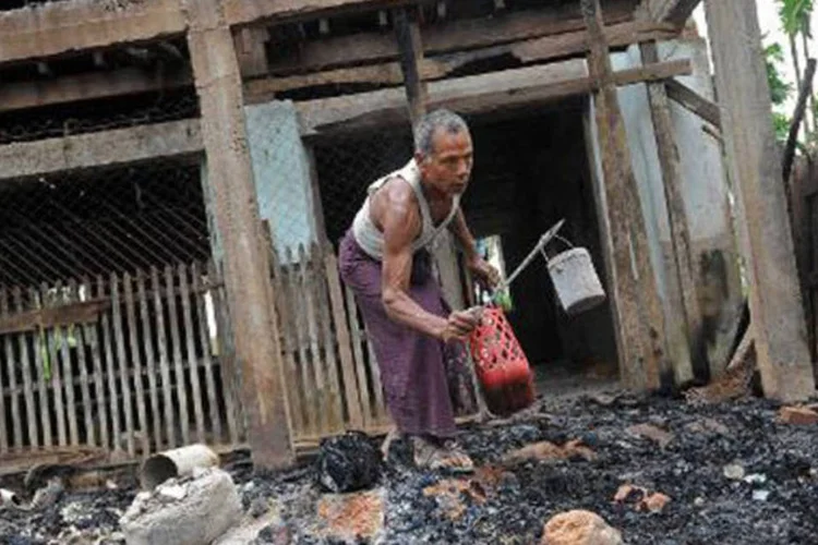 Homem recolhe objetos de uma mesquita incendiada em Mianmar: ataques às casas de muçulmanos começaram no fim de semana passado (Soe Than Win/AFP)