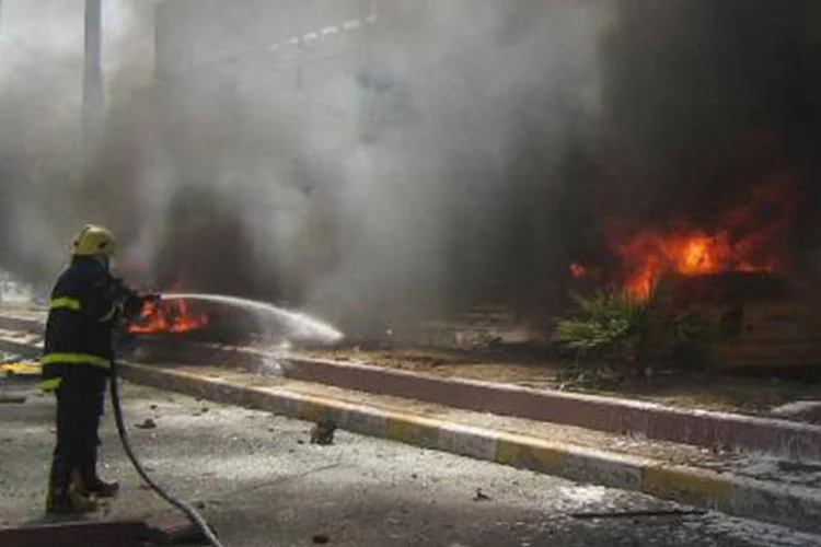 Bombeiro iraquiano combate as chamas causadas por um atentado: atentado tinha como alvo um posto de controle militar (Marwan Ibrahim/AFP)