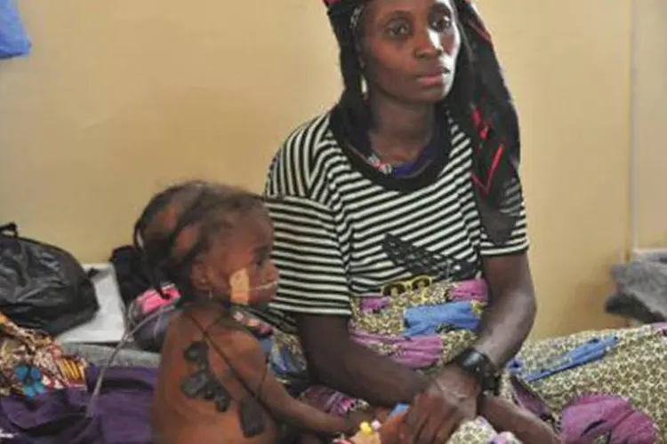 Menina de três anos, que sofre de desnutrição severa, com sua mãe: "foram registrados 79.087 casos de desnutrição aguda severa, e 362 mortes", afirma comunicado (Issouf Sanogo/AFP)