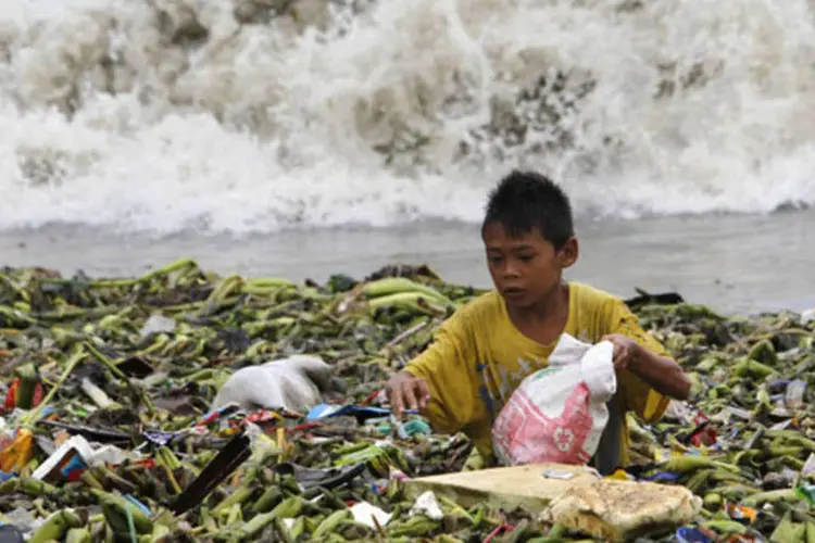 Garoto em meio a lixo trazido pelo tufão Utor: tufão é o mais forte que atingiu as Filipinas neste ano (Romeo Ranoco/Reuters)