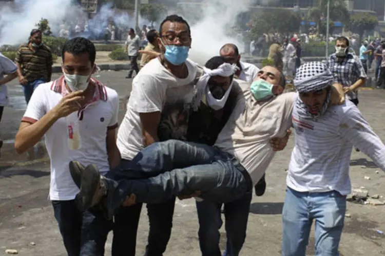 
	Manifestantes retiram ferido de local de confrontos no Egito: for&ccedil;as de seguran&ccedil;a lan&ccedil;aram g&aacute;s que supostamente causou as mortes
 (Asmaa Waguih/Reuters)
