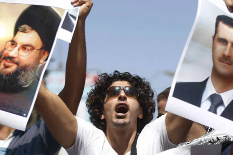 Palestino com imagens do presidente sírio Bashar al-Assad (d) e do líder do Hezbollah Sayyed Hassan Nasrallah: organização tem grande arsenal, segundo militar (Mohamad Torokman/Reuters)
