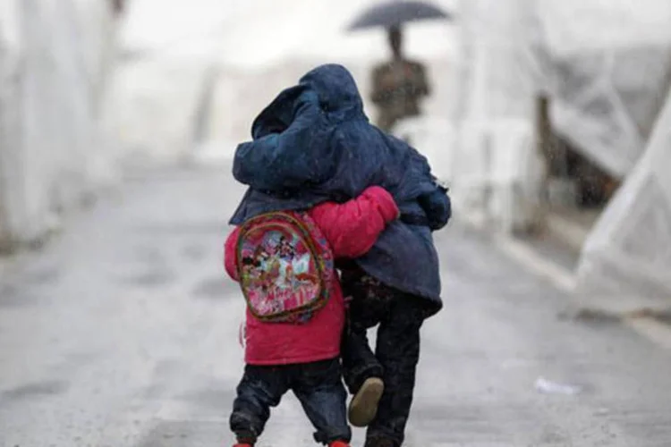 Crianças sírias caminham sob a chuva em campo de refugiados: muitos sírios vivem em tendas ou em casas maltratadas, com acesso limitado a água potável e serviços sanitários (Murad Sezer/Reuters)
