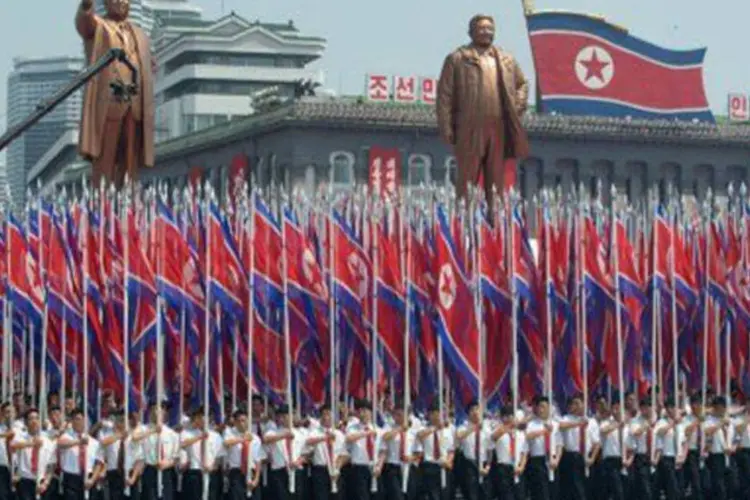 
	Norte-coreanos erguem bandeiras em desfile militar: comunicado foi divulgado ap&oacute;s v&aacute;rias semanas de relativa calma nas rela&ccedil;&otilde;es diplom&aacute;ticas entre os dois pa&iacute;ses
 (Ed Jones/AFP)