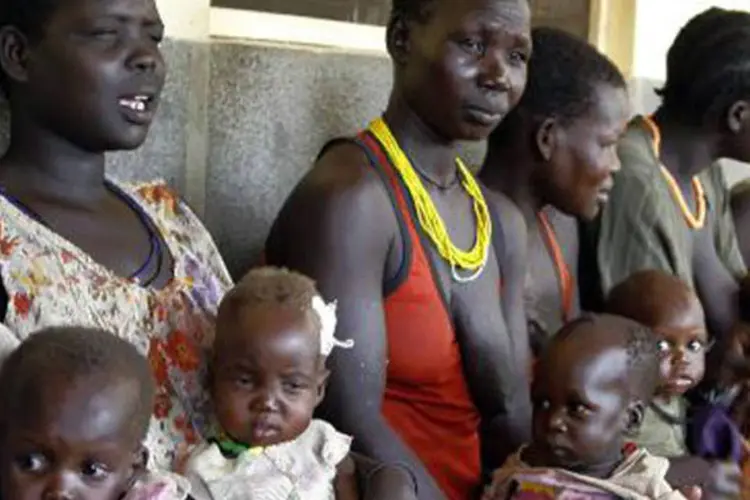 Mulheres seguram seus bebês, esperando tratamento contra desnutrição: entre 1990 e 2012, número de mortes de crianças passou de 12,6 a 6,6 milhões no mundo (Peter Busomoke/AFP)