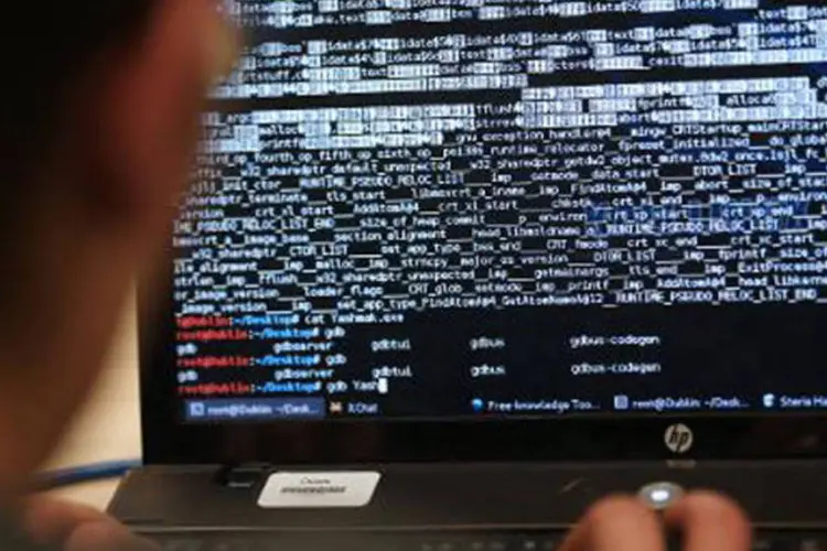 
	Rapaz opera um computador em competi&ccedil;&atilde;o de hackers
 (Thomas Samson/AFP)