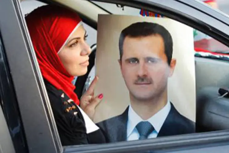 Mulher síria segura um retrato do presidente sírio, Bashar al-Assad: Assad disse ainda que a posição russa pode contribuir para criar um "novo equilíbrio mundial" (Anwar Amro/AFP)