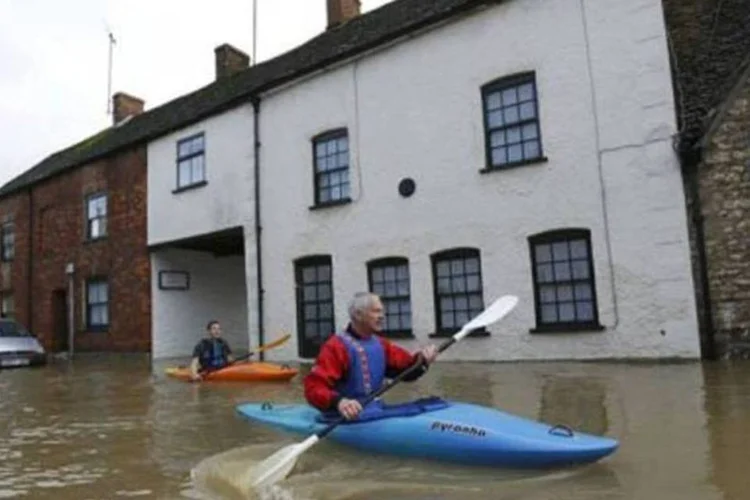Moradores usam canoas para cruzar as ruas inundadas em Malmesbury, Grã-Bretanha (AFP / Justin Tallis)