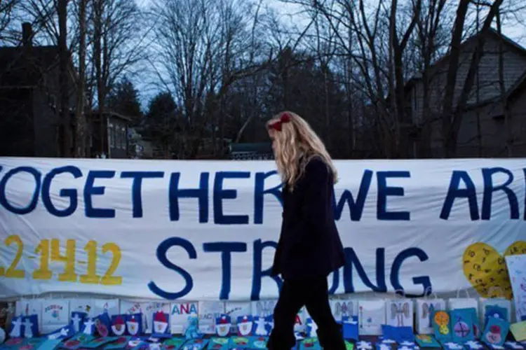 
	Mulher passa por memorial criado em mem&oacute;ria das v&iacute;timas da escola Sandy Hook: o novo col&eacute;gio foi pintado, limpo e acondicionado para receber as 500 crian&ccedil;as
 (Andrew Burton/AFP)