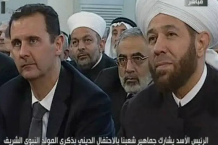 Imagem da televisão síria mostra o presidente Bashar al-Assad (E) em uma cerimônia religiosa em Damasco em 24 de janeiro
 (AFP)