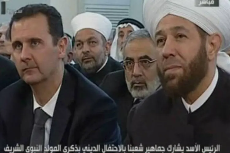Imagem da televisão síria mostra o presidente Bashar al-Assad (E) em uma cerimônia religiosa em Damasco em 24 de janeiro (AFP)